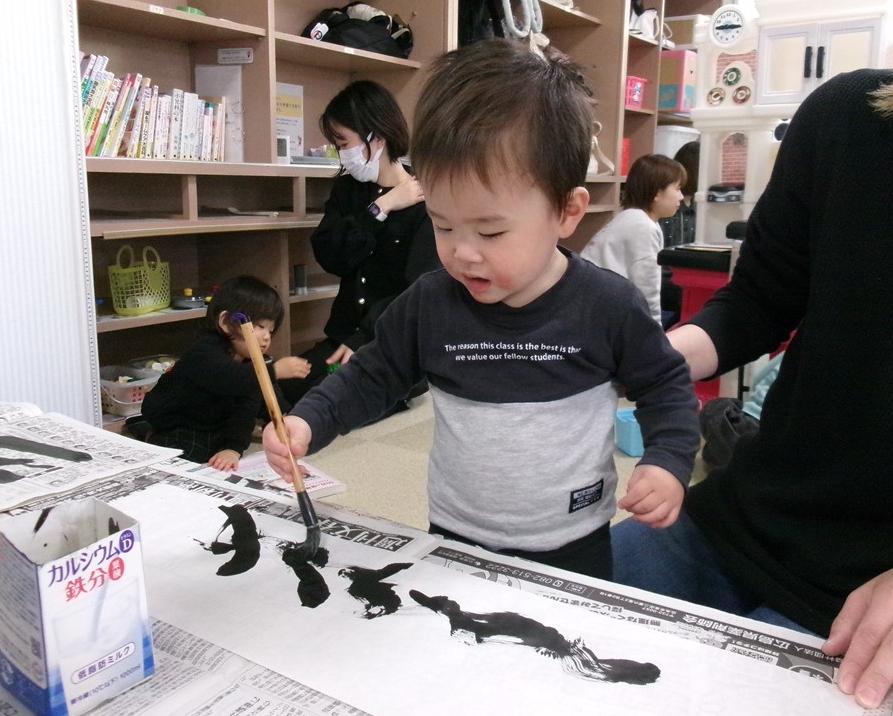 真剣な表情で筆を使って作品を作る子どもの写真
