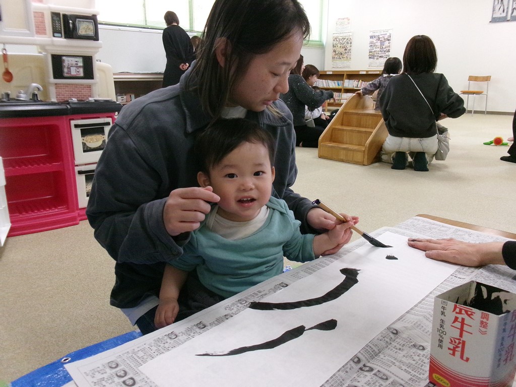 母と一緒に子どもが書道をしている写真
