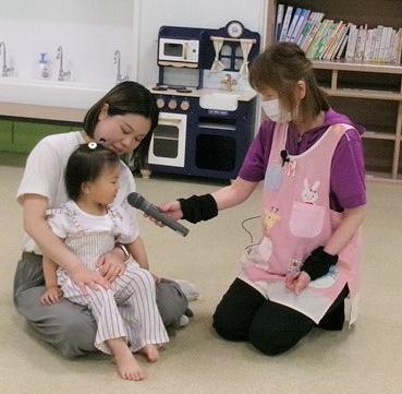 6月わくわくキッズでインタビューをする保育士と親子の様子
