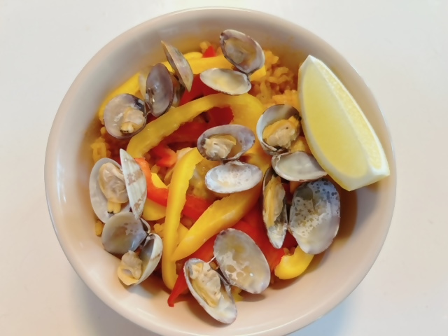 レモン付きのパエリアが盛られた皿の写真