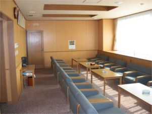 青い椅子が机を挟んで向かい合わせに横一列で並んでいる部屋の写真