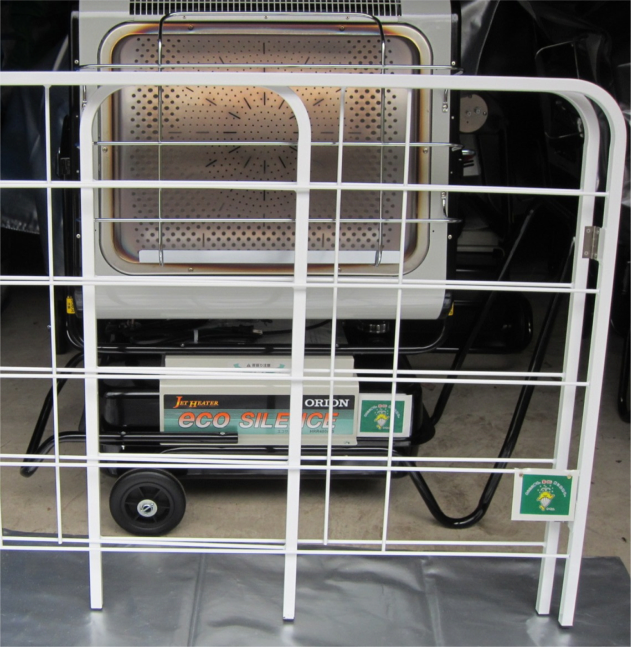 白い枠組みの奥に置かれている車輪のついた黒いフレームが付いた大型ジェットヒーターの写真