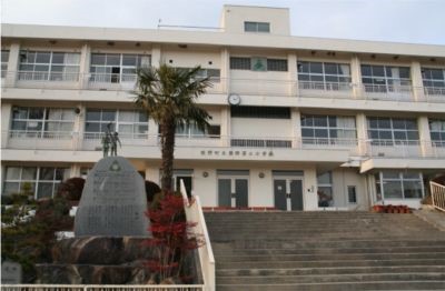 校舎正面の階段と記念碑、ヤシの木が写った学校玄関前の写真