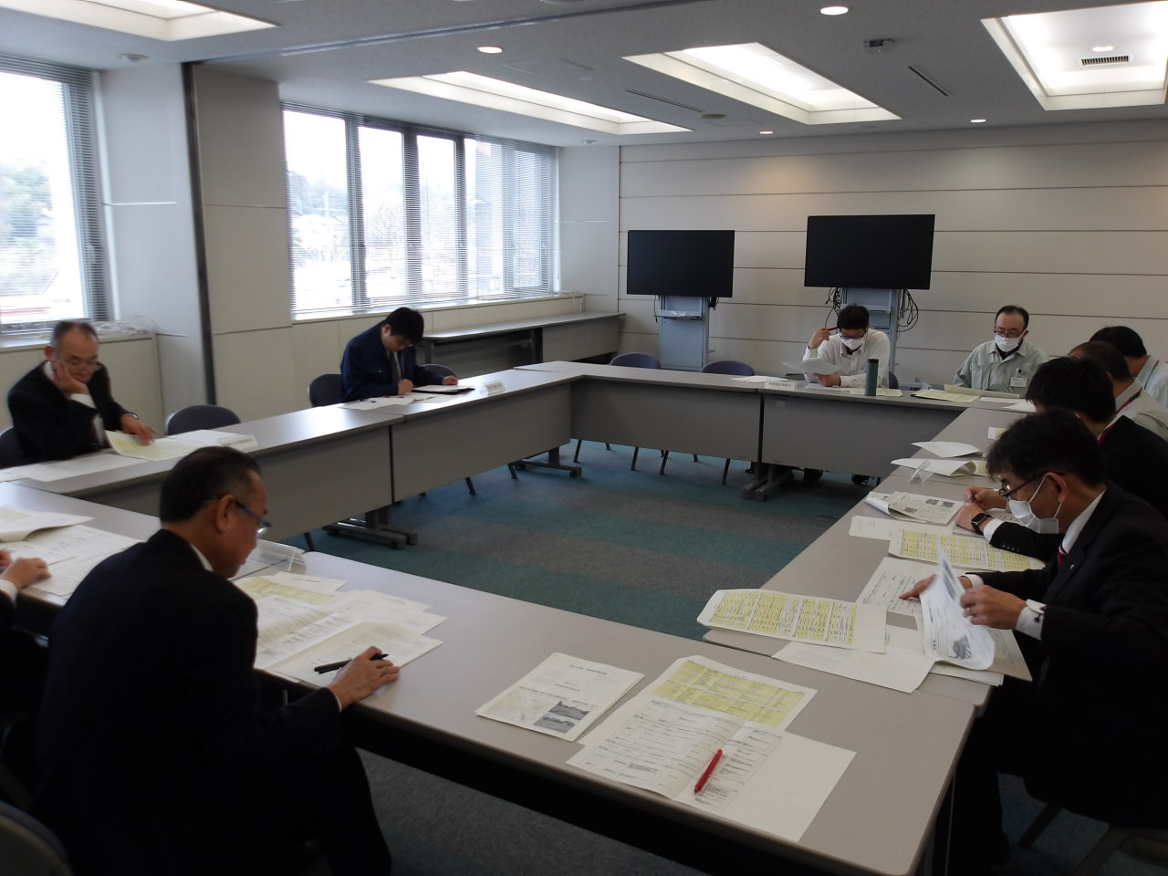 会議室の机を囲んで資料を確認しながら協議している参加者たちの写真