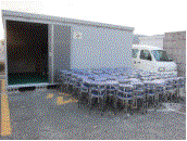 外に設置された倉庫前に丸椅子210脚が綺麗に整列されている写真