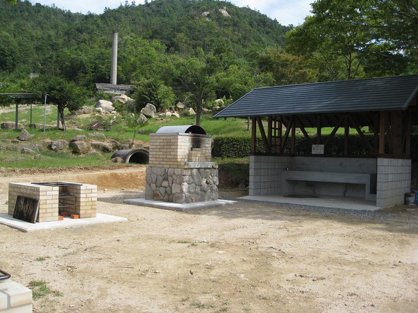 森に囲まれたかまど・炉が置いてある広場の写真