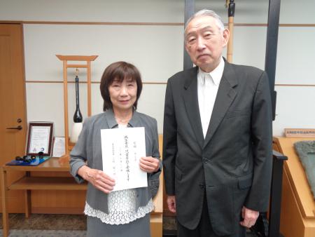 委嘱状を持って記念撮影に臨む尼崎さんと熊野町長の写真