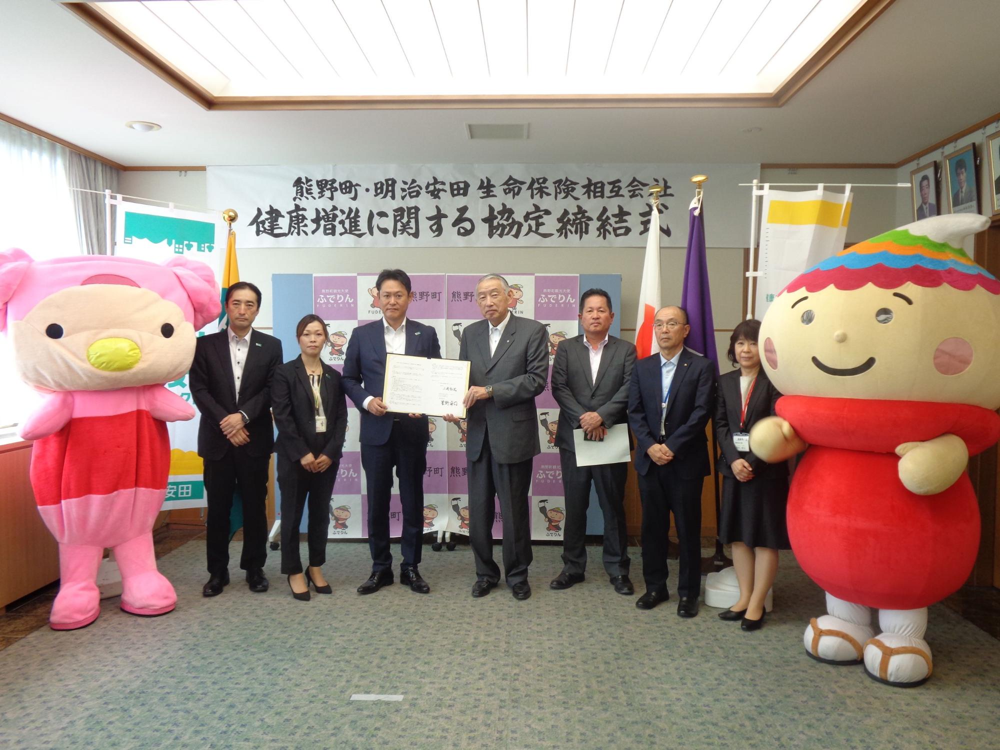 協定締結式で記念撮影に臨む熊野町長、明治安田生命保険相互会社の関係者、ゆるキャラふでりんの写真