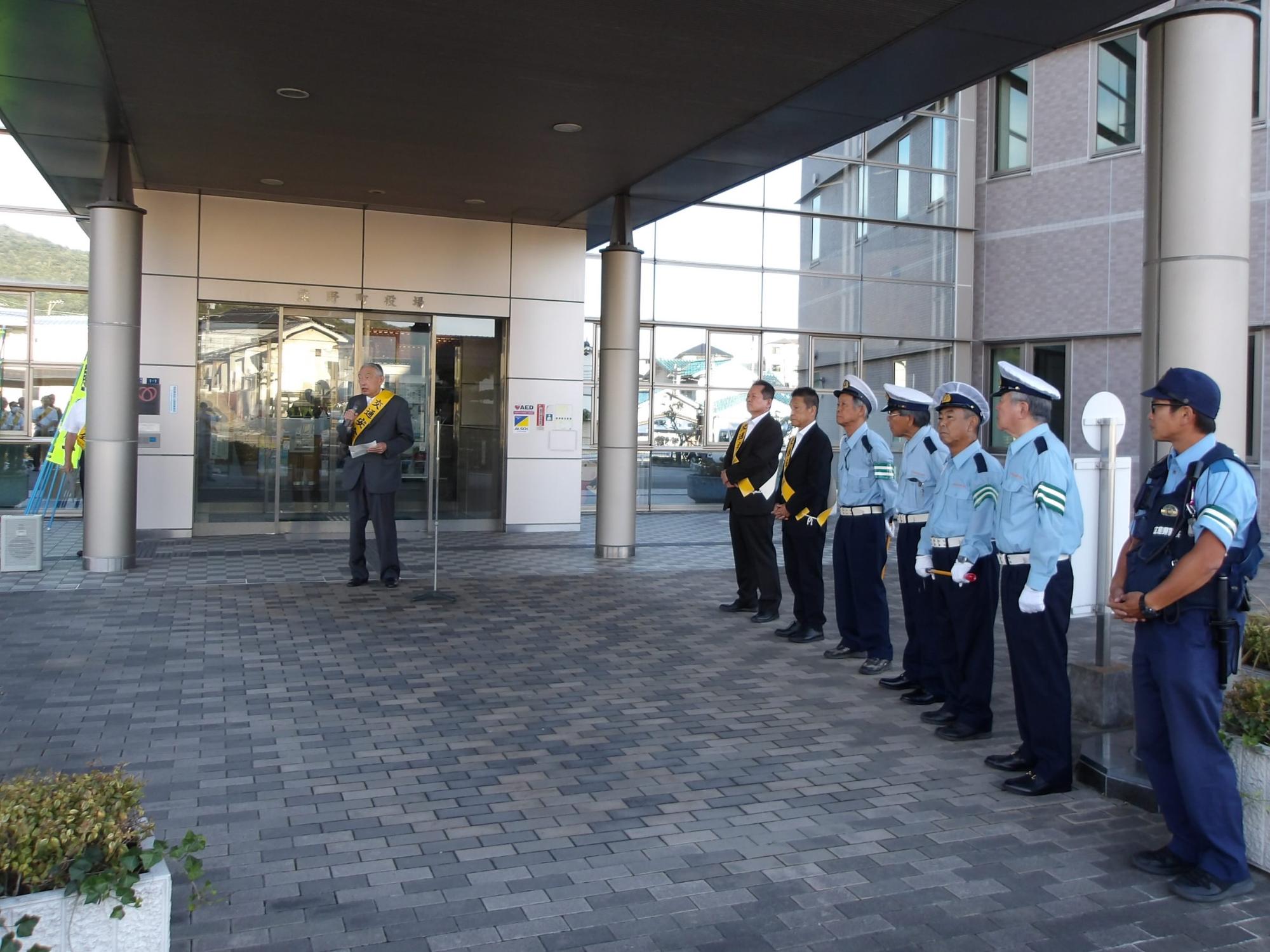 熊野町役場の入り口で警察官に激励の挨拶をしている熊野町長の写真