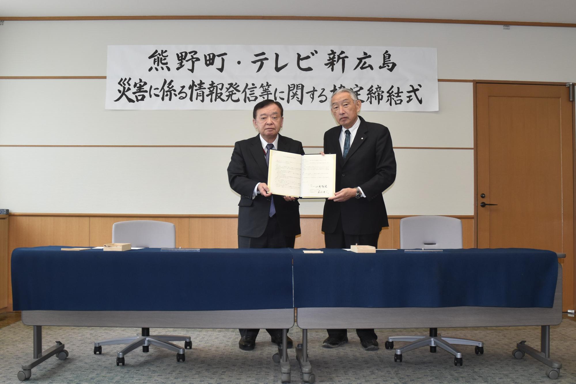 締結した書類を持ち記念撮影に臨む熊野町長、テレビ新広島の代表の写真