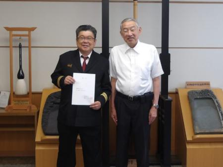 交付された消防団長の辞令を手にし記念撮影に臨む梶山龍生さんと熊野町長の写真