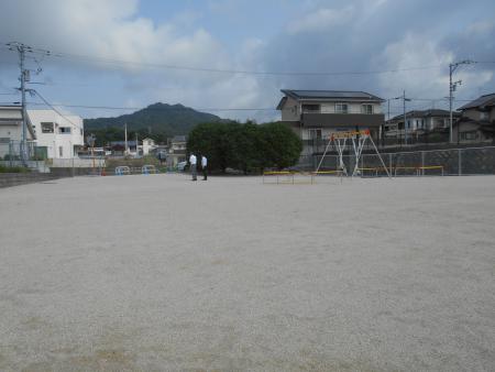 ブランコの前に低木が植えられている公園の写真