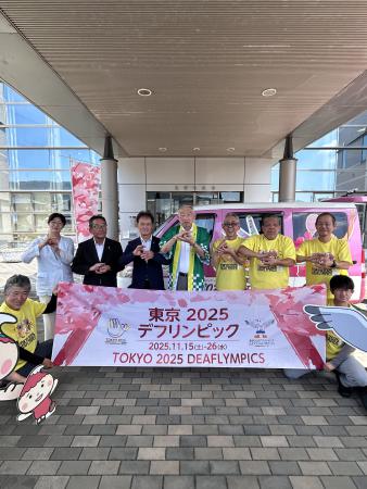 東京 2025デフリンピックと書かれた横断幕の後ろで記念撮影に臨む熊野町長と関係者の方々の写真