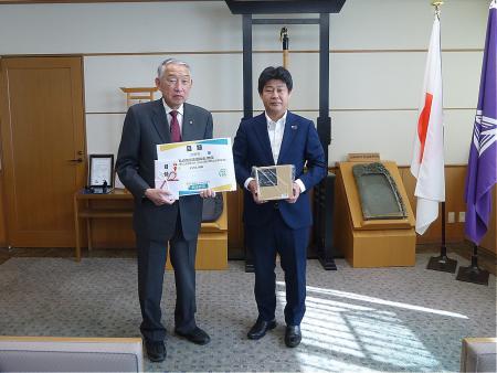 目録を持ちながら熊野町長との記念撮影に臨む明治安田生命保険相互会社広島支社の担当者の写真