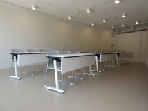 白い机が並んでいる講義室の写真