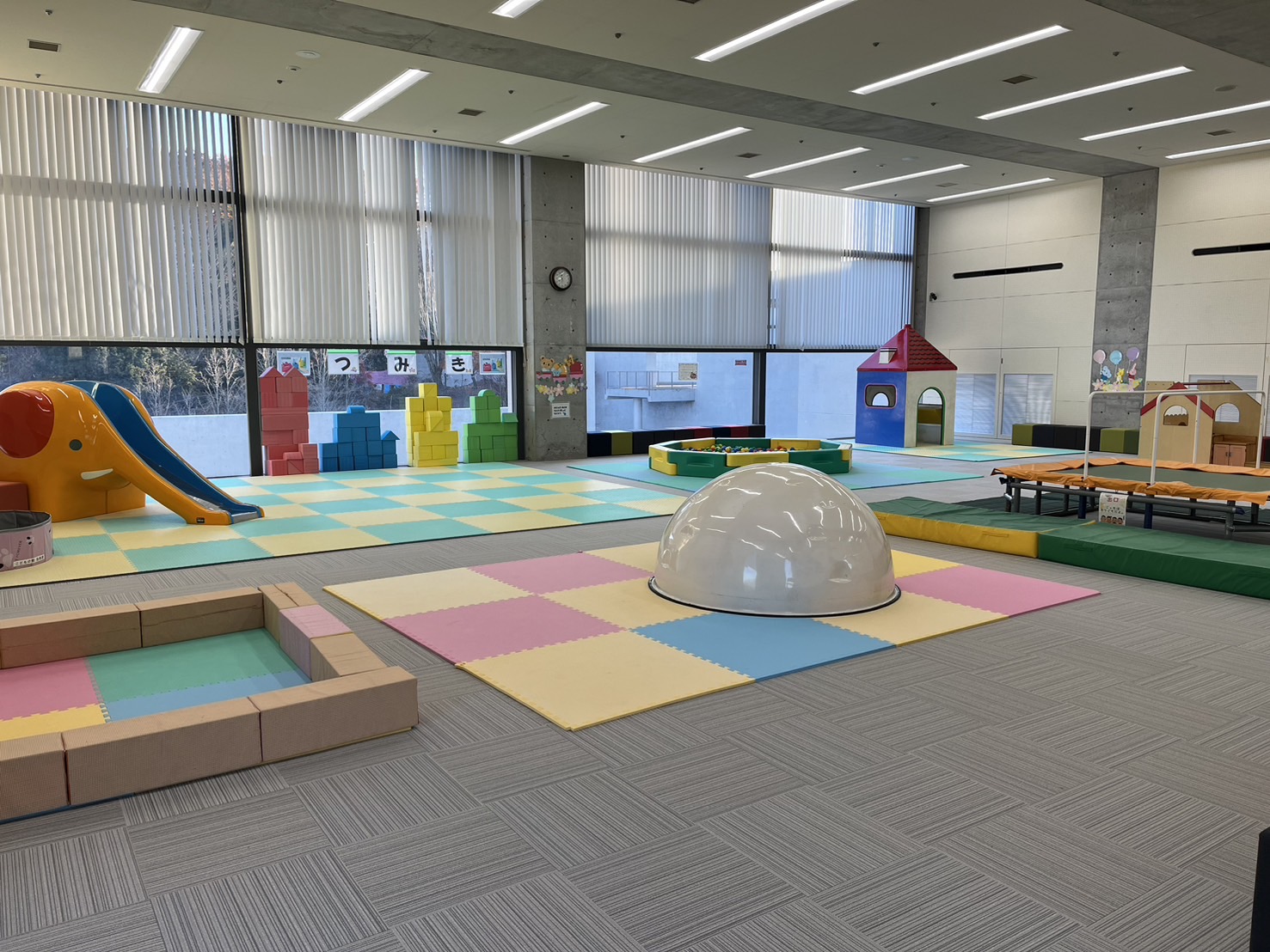象の滑り台や積み木があり、色とりどりの床パネルが敷き詰められている親子遊戯室の写真