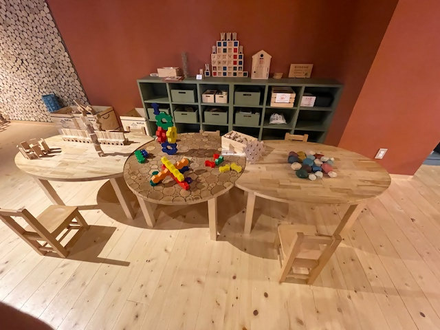 木製の丸テーブルに積み木などのおもちゃが並べられている写真