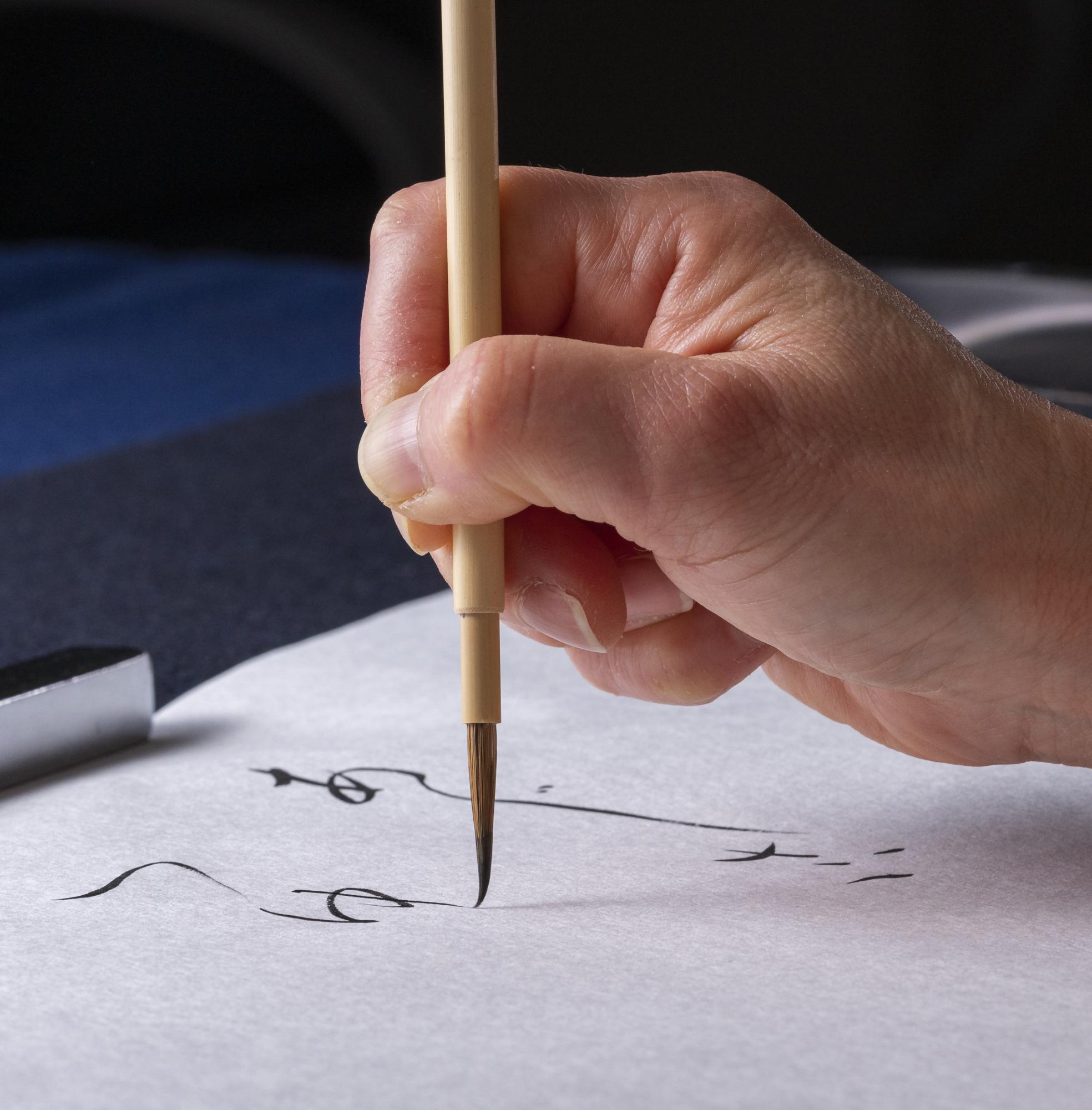 毛筆で半紙にひらがなを書いているクローズアップ写真