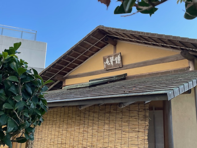 「鐘聲庵」の看板が掲げられ、すだれがかかっている茶室の入り口を捉えた写真