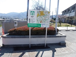 敷地前の植え込みの手前に案内板が設置されている写真