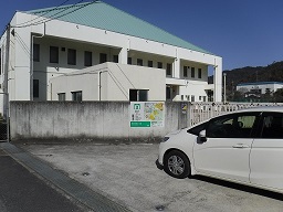 駐車場に接した塀に案内板が設置されている写真
