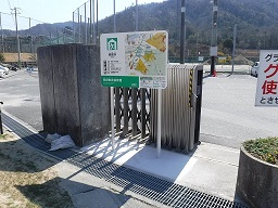 広い敷地手前の門扉の前に案内板が設置されている写真