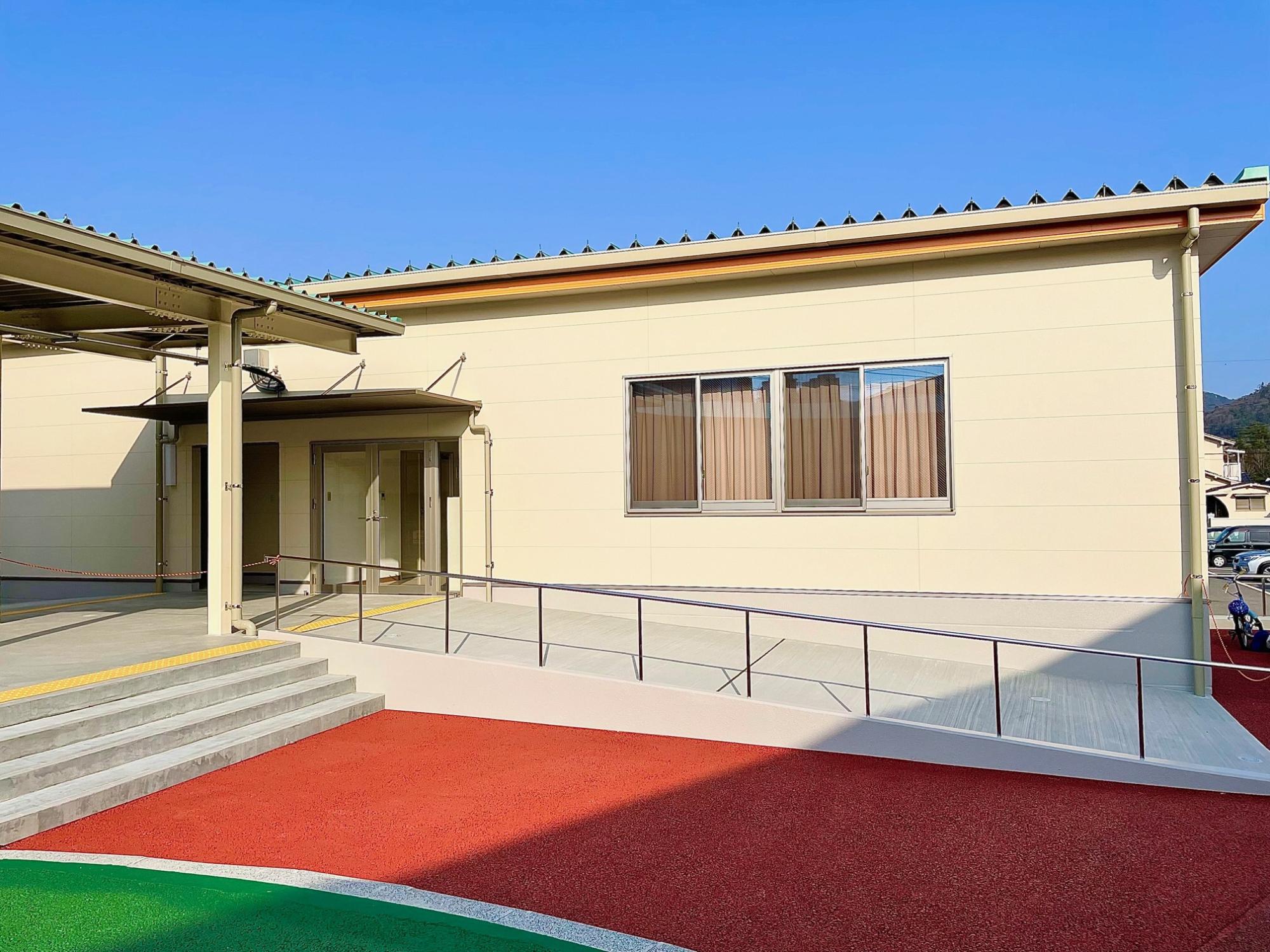 階段とスロープが設置されたクリーム色の建物の写真