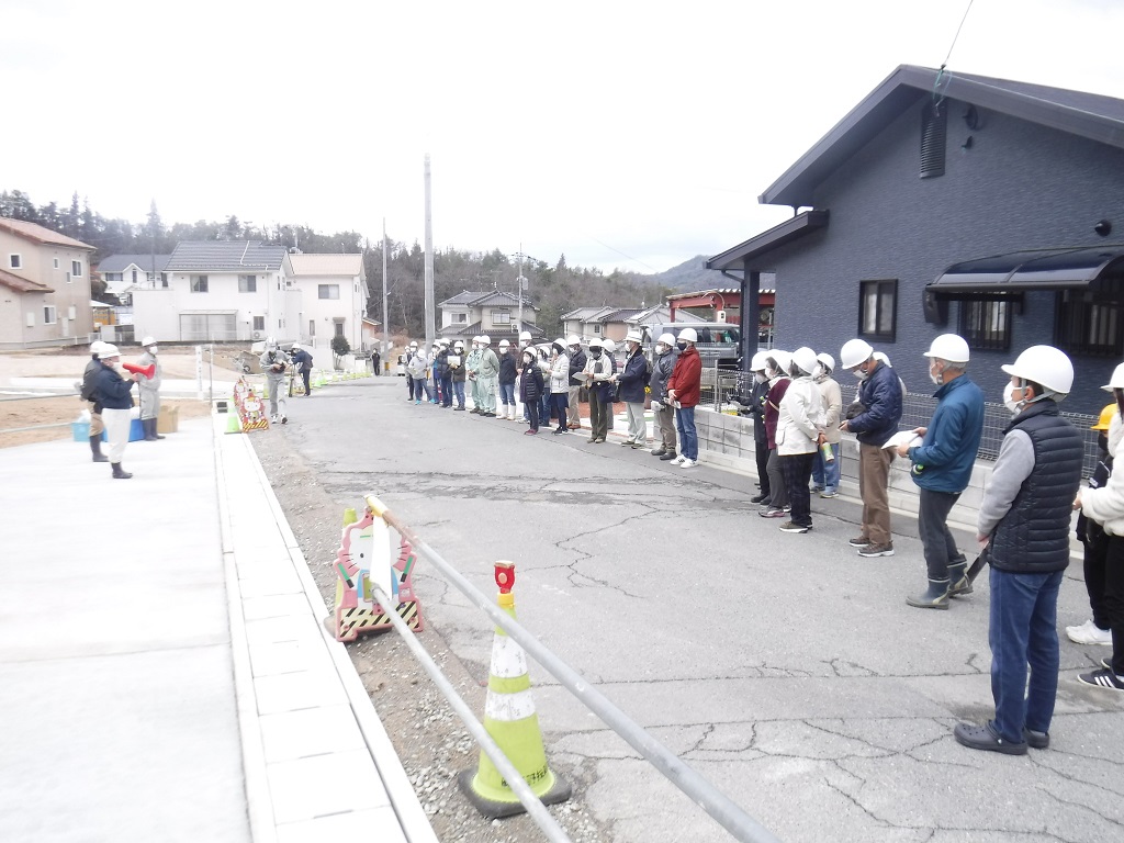 メガホンを手にした男性の話を聞くヘルメットとマスクを付けた人々の写真