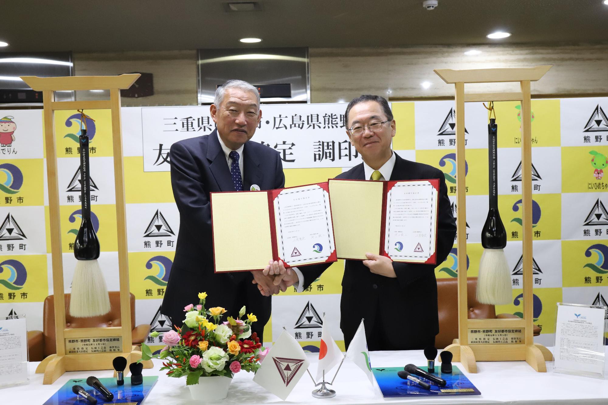 手に証書を持った2人の男性が並んでいる写真