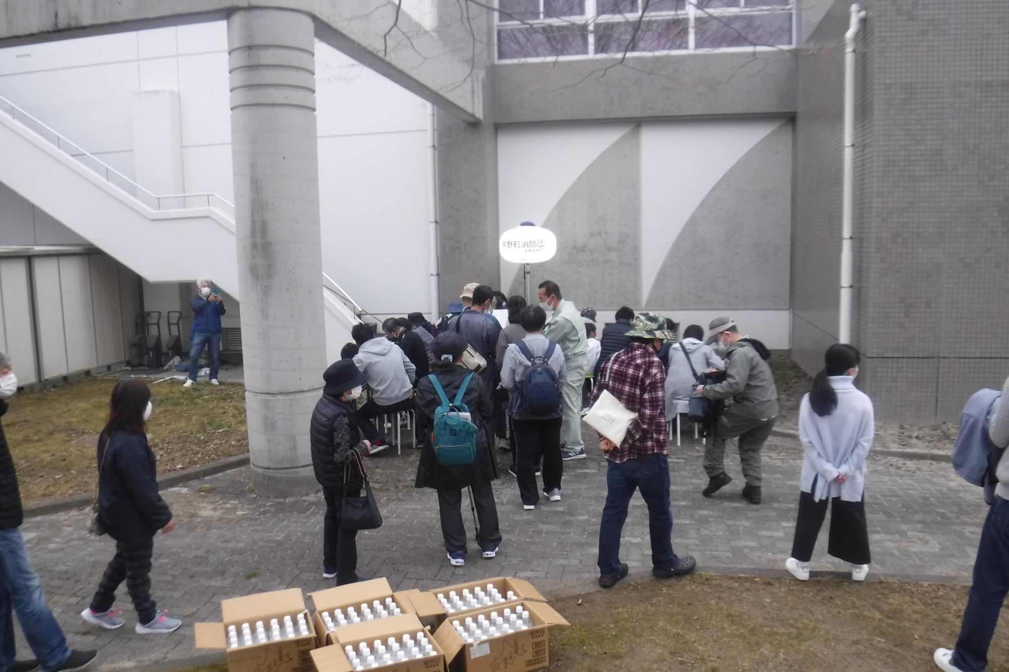 灰色の建物のそばで集まる人々の写真