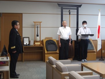 ワイシャツ姿の男性2人の近くで制服姿の男性が立っている写真