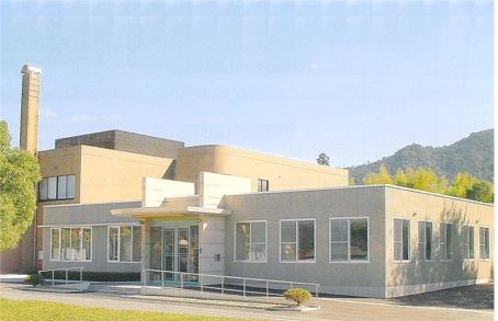 青空の下に周りを木々に囲まれた建物の写真