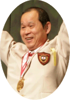 男性が首からメダルを下げて両手を挙げている写真