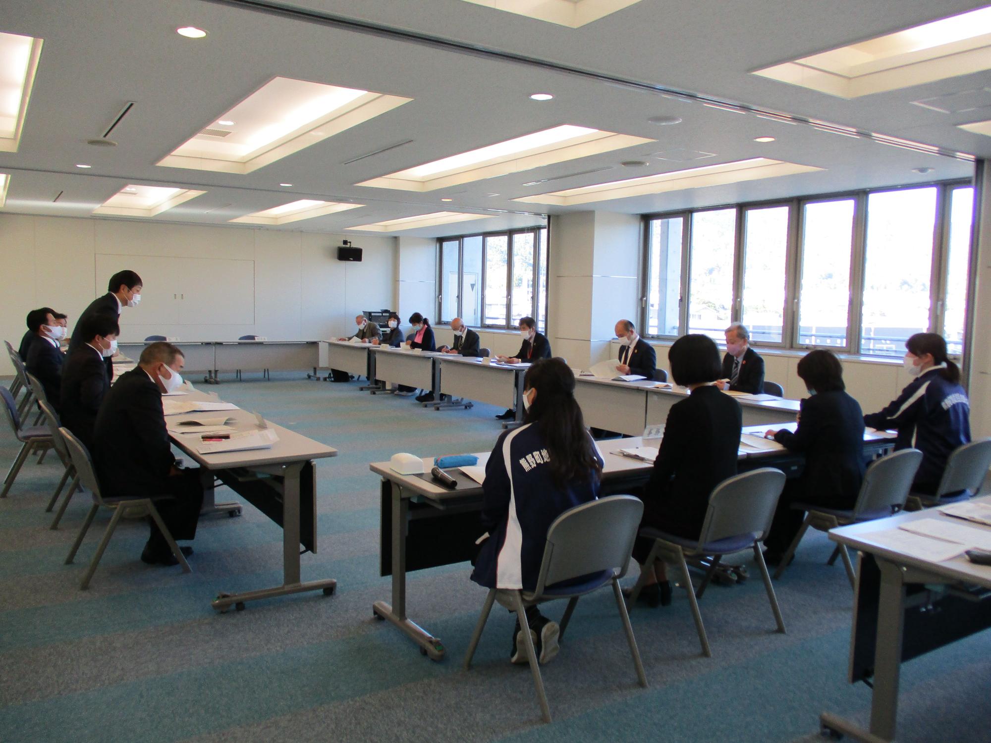 会議室内に四角に並べられた机にむかって座り、会議している様子の写真