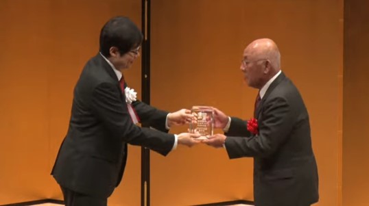男性2名が横向きでトロフィーを受け取っている写真