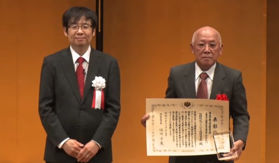 男性2名が正面を向いて表彰状を掲げている写真