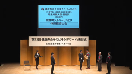 室内で6名の人たちが表彰式を行っている写真