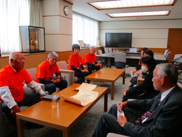 室内で椅子に座っている人たちが話し合いを行っている写真