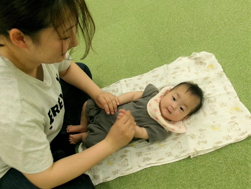 5月ベビーマッサージをする母とそれを受ける子どもの様子