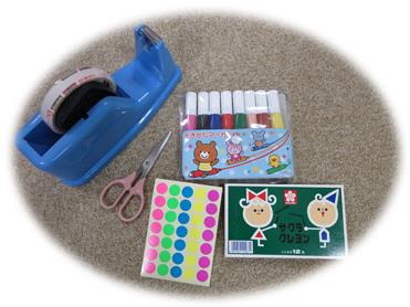 セロテープ、ハサミ、シール、ペン、クレヨンが並んで置かれている写真