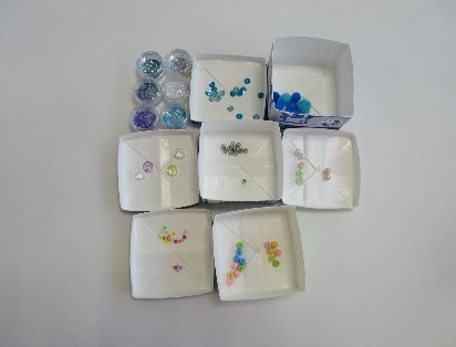 牛乳パックで作られた箱にビーズなどが入っている写真