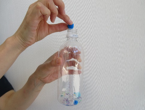 空のペットボトルにビーズやラメを入れている写真