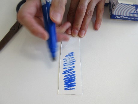 細長い紙に水色のペンで線を描いている写真