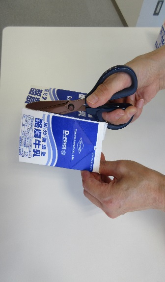 半分に切られた牛乳パックにハサミを入れている写真