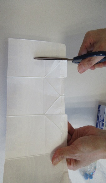 開かれた牛乳パックの内側にハサミを入れている写真