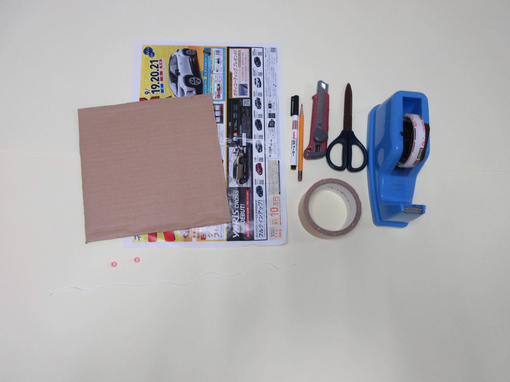 チラシ、カッター、ハサミ、セロテープが並んで置かれている写真