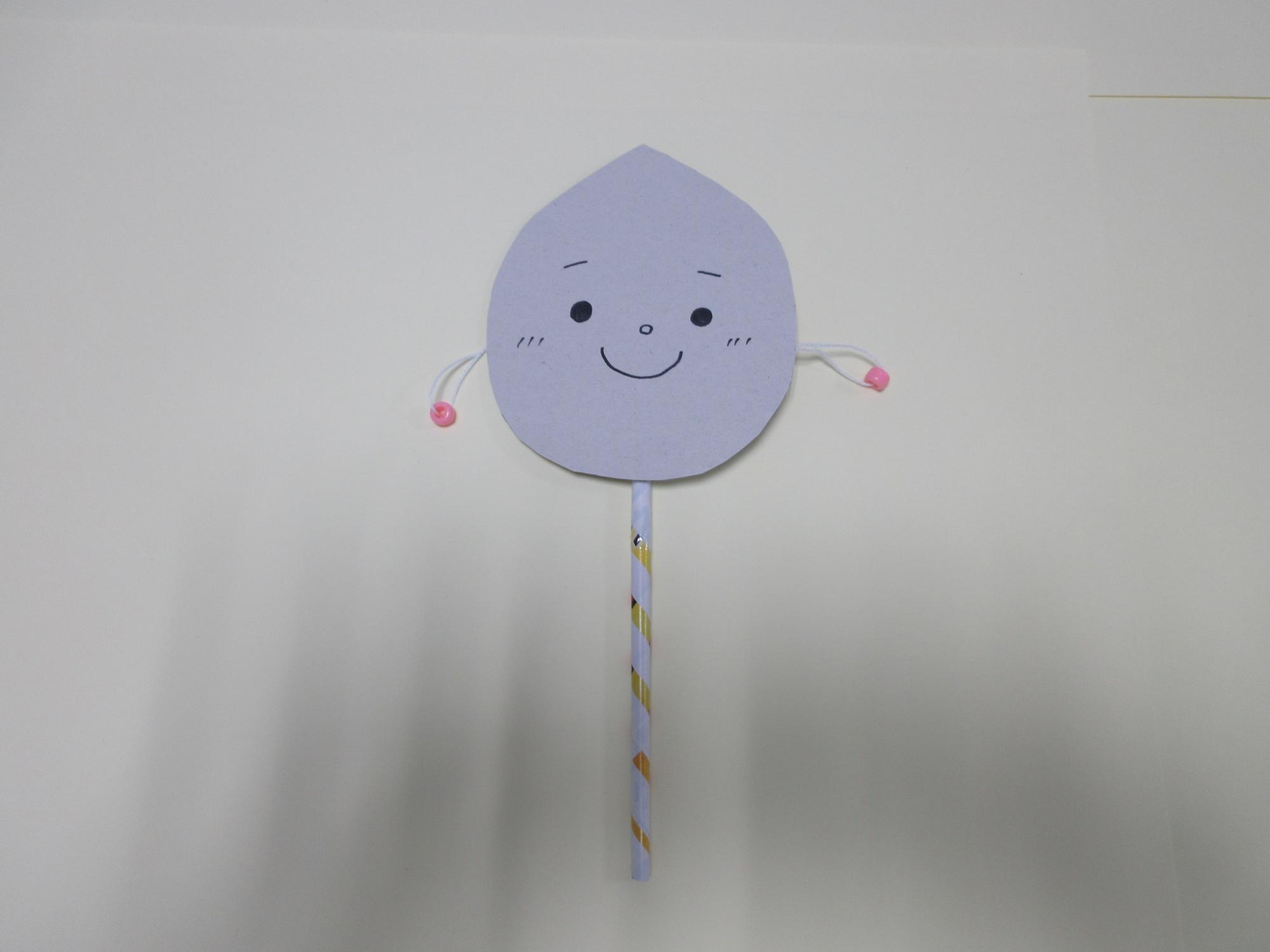 顔の描かれた灰色の紙に細長い紙や紐が付けられている写真