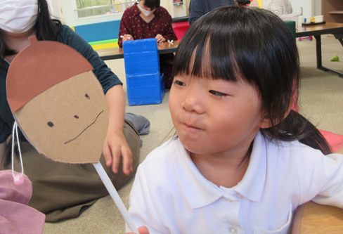 厚紙で作られたどんぐりのキャラクターを見ている子供の写真