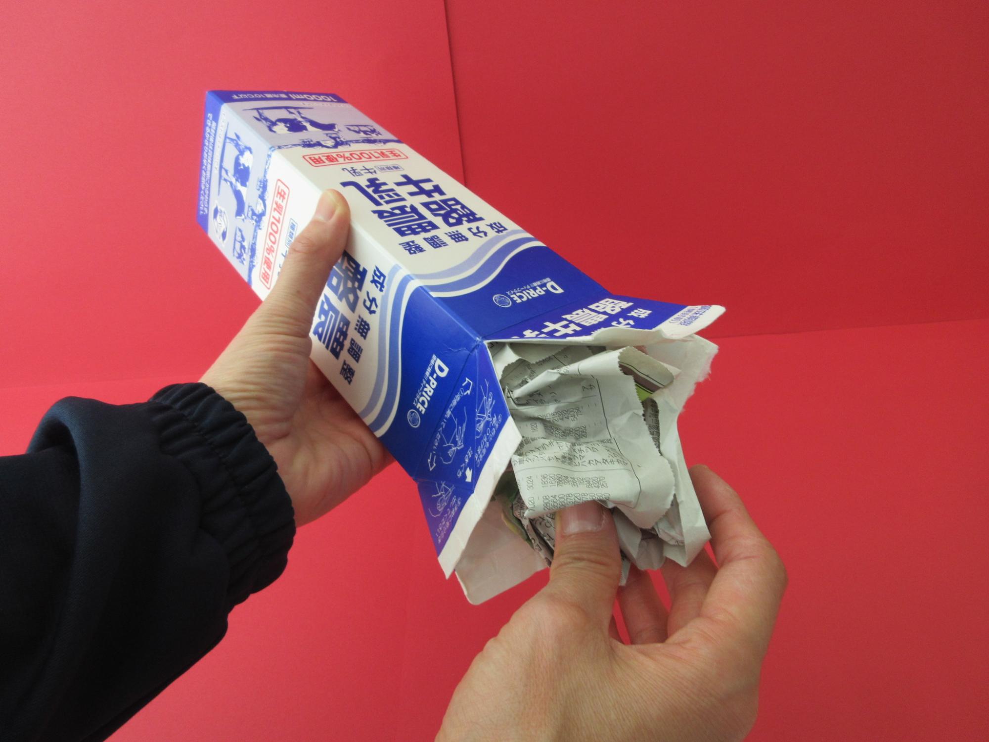牛乳パックの中に新聞紙を入れている写真