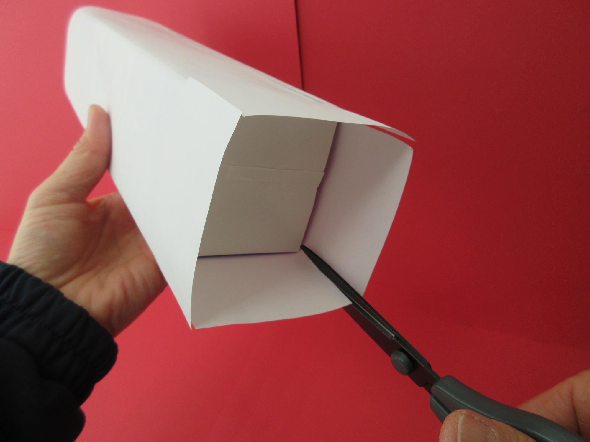 四角い箱を包んでいる白い紙にハサミで切り込みを入れている写真